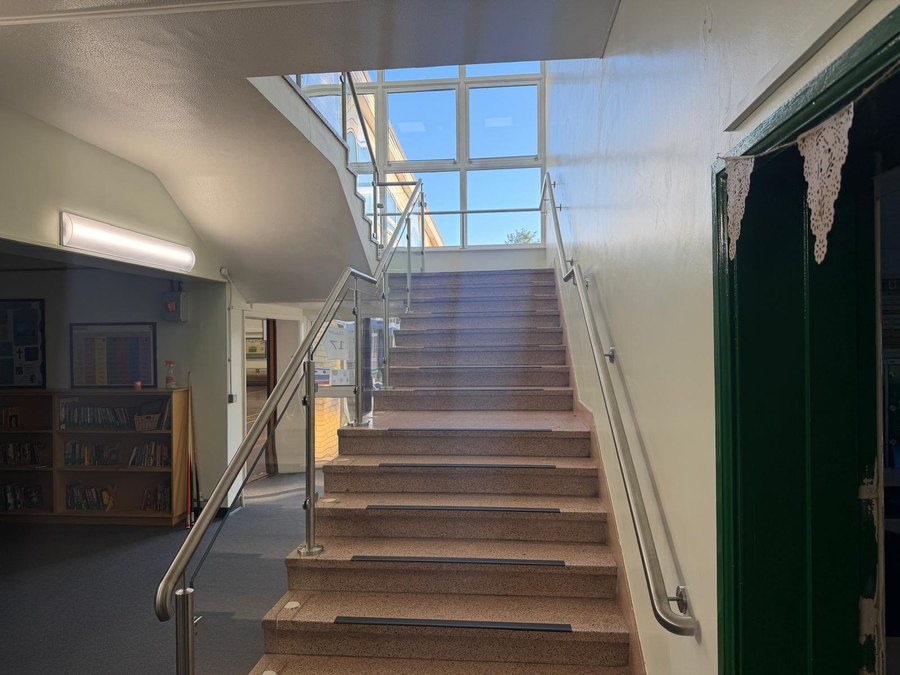 Stainless steel wall rail returning cleanly into the wall at the end of a school staircase